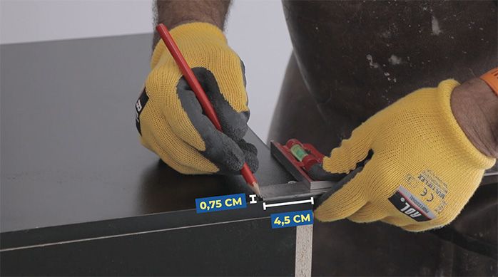 un hombre marca la fijación del fondo del mueble gamer horizontal en la melamina
