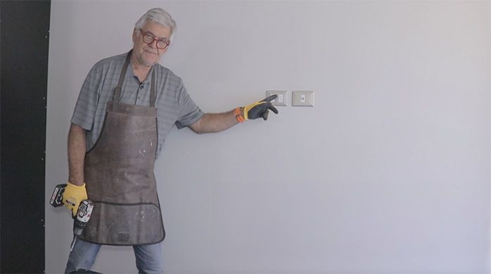 un hombre muestra los enchufes de una pared