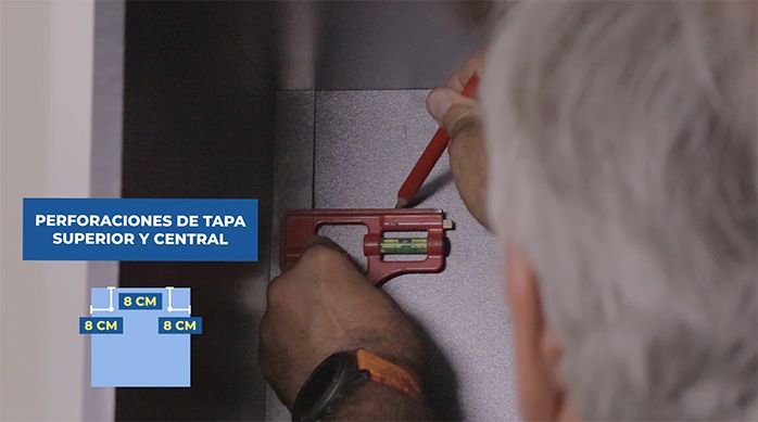 un hombre marca las fijaciones internas del mueble gamer vertical para fijarlo al muro