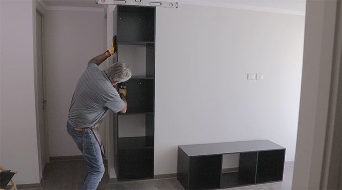 un hombre fija el mueble gamer vertical en el muro