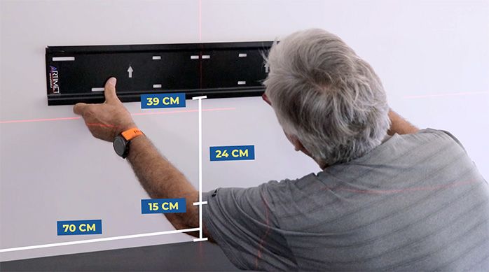 un hombre presenta una parte del soporte para tv sobre el mueble gamer horizontal, a 39 cm de distancia
