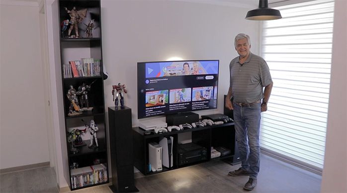 un hombre junto a una estación gamer que incluye un mueble gamer vertical y uno horizontal
