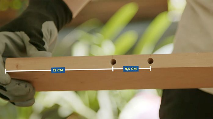 un hombre muestra un trozo de madera con dos perforaciones