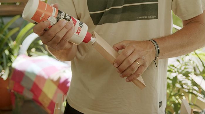 un hombre aplica cola fría en el canto de un trozo de madera