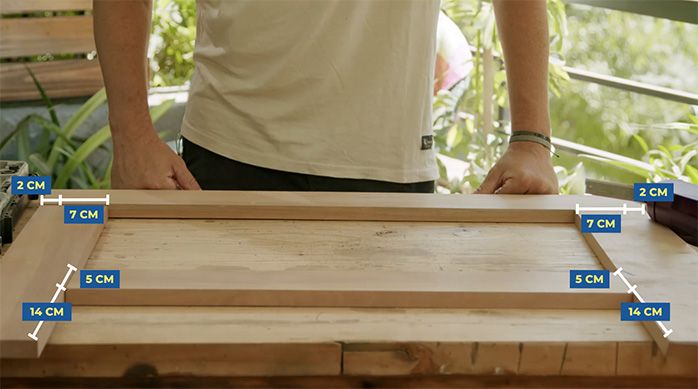 un hombre frente a los trozos de madera formando la estructura trasera de la mesa plegable de madera