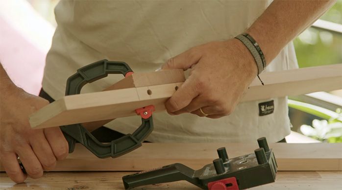 un hombre pone una prensa para juntar dos trozos de madera