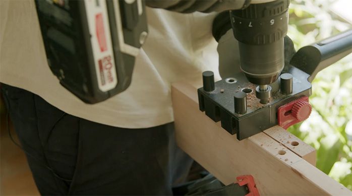 un hombre perfora el canto de un trozo de madera