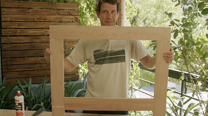 un hombre muestra la estructura trasera de la mesa plegable de madera