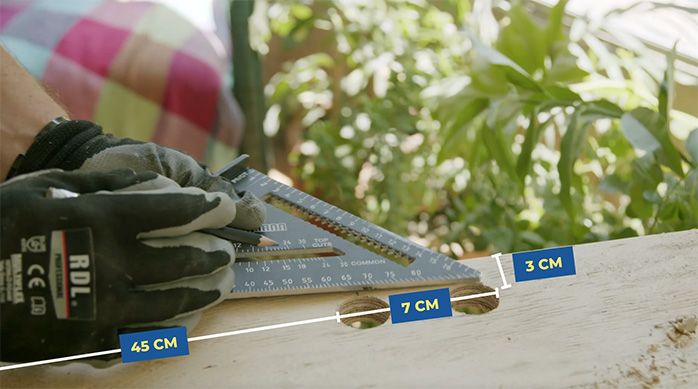 un hombre marca el lugar del calado para hacer la manilla de la mesa plegable de madera
