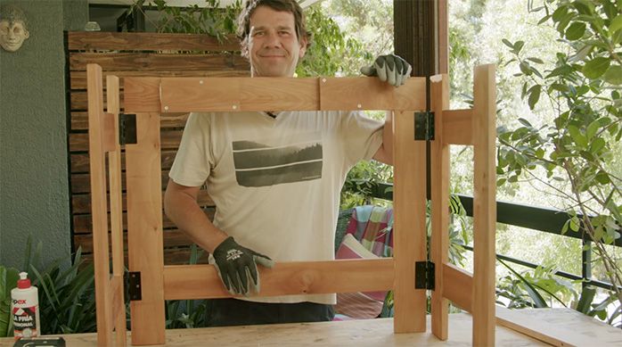 un hombre muestra la base de la mesa plegable de madera