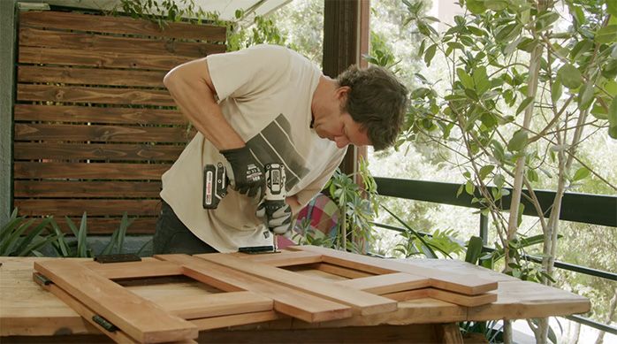 un hombre fija las bisagras de la mesa plegable de madera