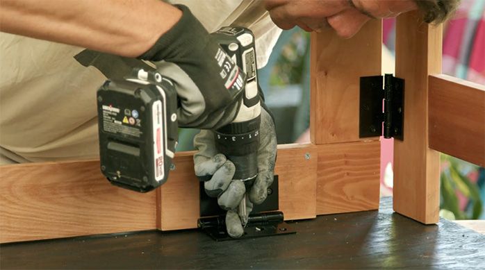 un hombre fija las bisagras de la mesa plegable de madera