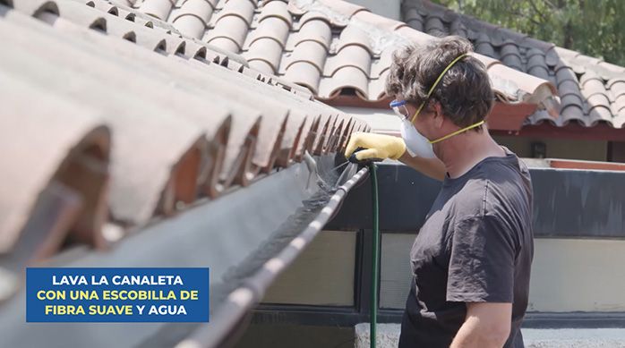 un hombre lava la canaleta de pvc con agua