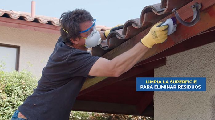 un hombre limpia el techo de una casa con una escobilla suave