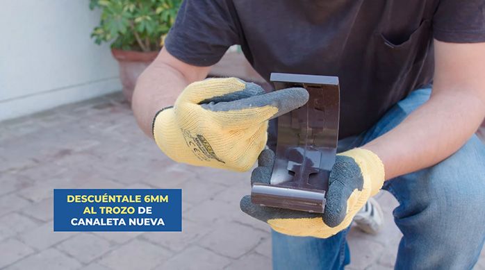 un hombre con guantes muestra una unión para canaletas