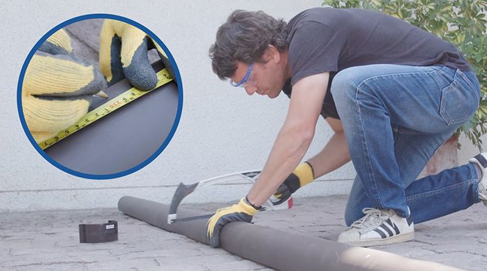 un hombre corta una canaleta de pvc con una sierra manual