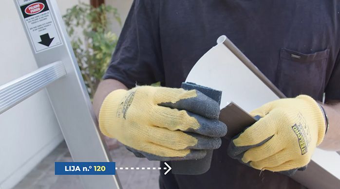 un hombre con guantes lija el borde cortado de una canaleta de pvc