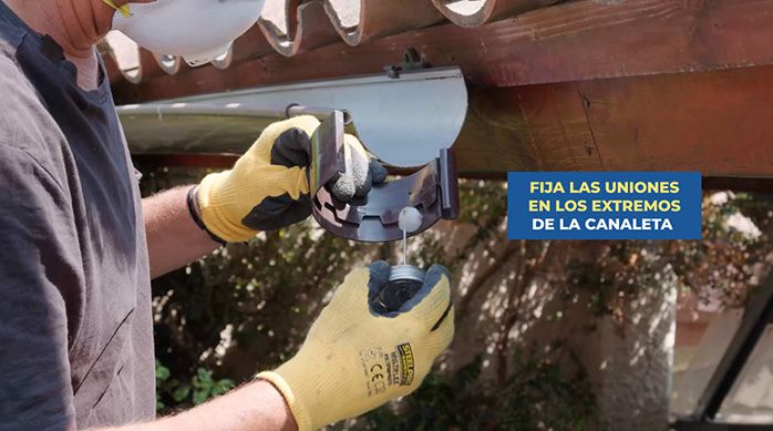 un hombre con guantes de trabajo aplica adhesivo para pvc vinilit en la unión para canaletas