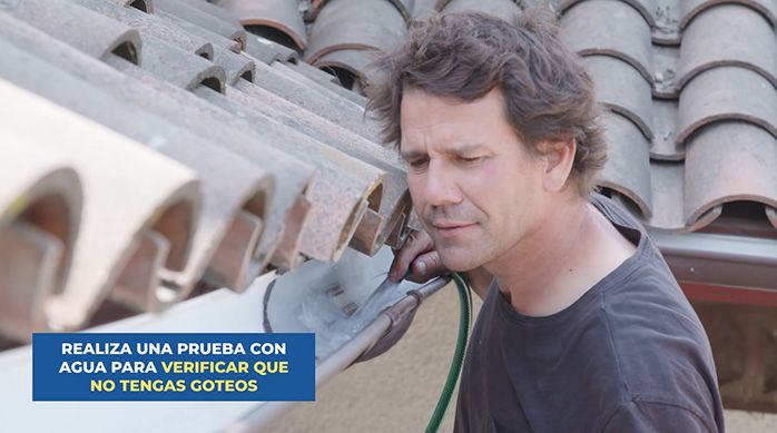 un hombre prueba la instalación de las canaletas de pvc poniendo agua en ellas con una manguera