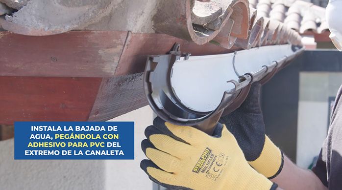 un hombre instala una bajada de agua en las canaletas de pvc