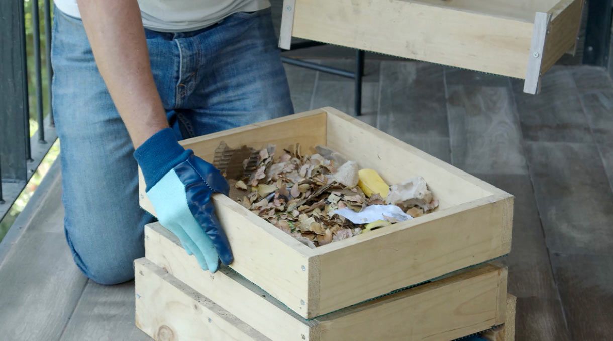 una persona mueve los cajones de la compostera de madera para departamento