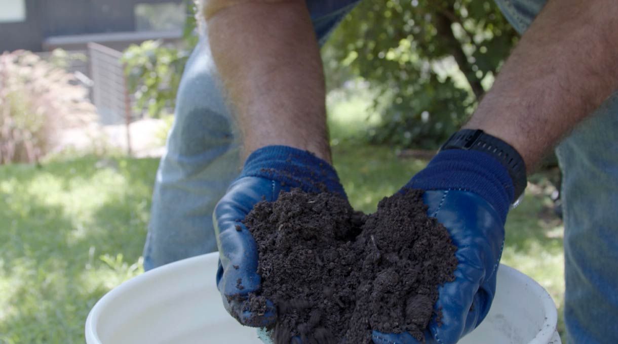un hombre sostiene compost terminado hecho en casa