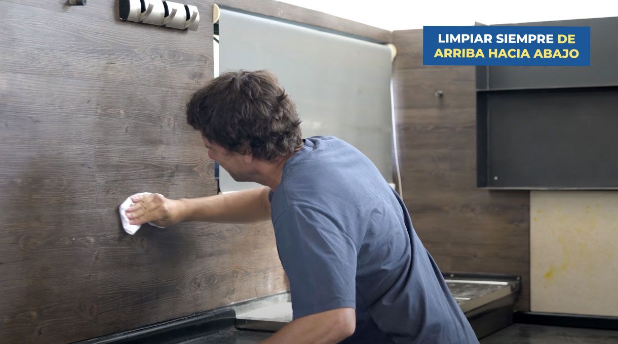 un hombre limpia la pared de una cocina con un trapo