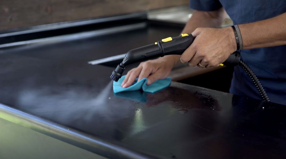 un hombre utiliza una máquina a vapor de alta temperatura para remover la suciedad de la cocina, para obtener una cocina limpia