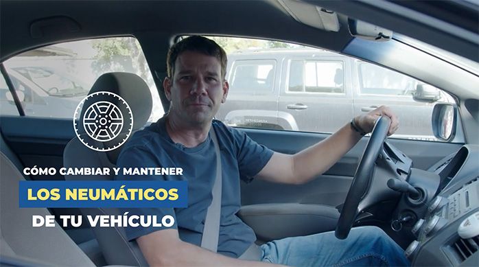 un hombre en un auto con cinturón de seguridad y una mano apoyada en el manubrio