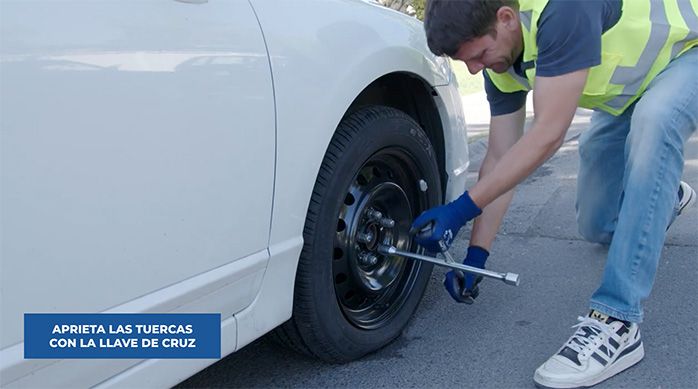 un hombre aprieta los pernos de un neumático con una llave cruz