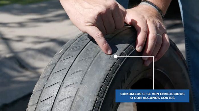 un hombre señala un corte en un neumático desgastado