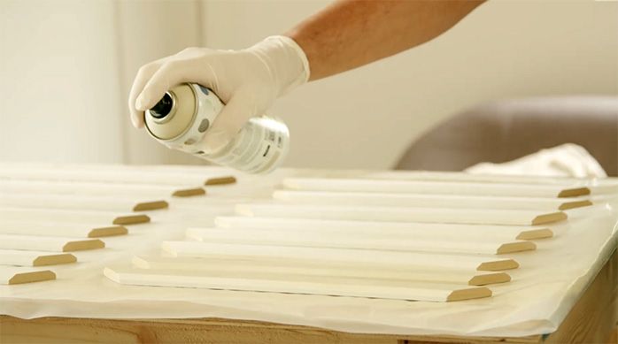 un hombre pinta con pintura en spray las molduras para el mueble organizador