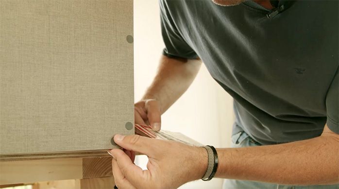 un hombre pone tapas adhesivas para cubrir los tornillos del mueble organizador
