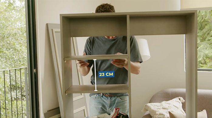 un hombre pone las repisas en el mueble organizador