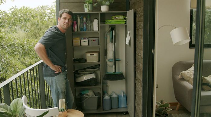 un hombre frente a un mueble organizador para artículos de limpieza terminado