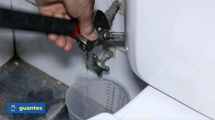 un hombre suelta el flexible del inodoro del baño