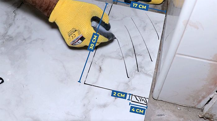 un hombre dibuja un corte en la plancha de porcelanato para baños