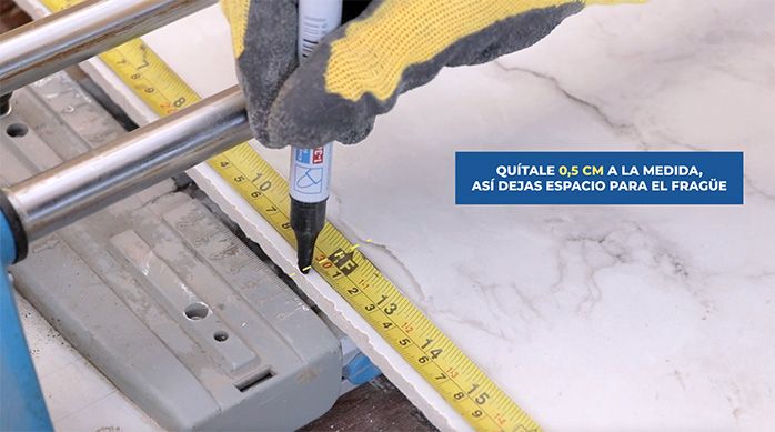 un hombre marca una medida en la plancha de porcelanato para baños