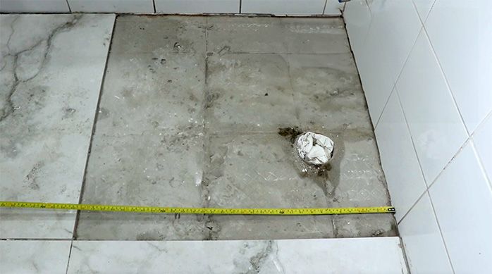 un hombre mide el corte de porcelanato necesario para terminar el piso de un baño
