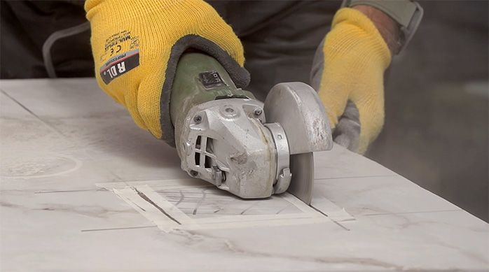 un hombre corta el porcelanato para baños con un esmeril angular