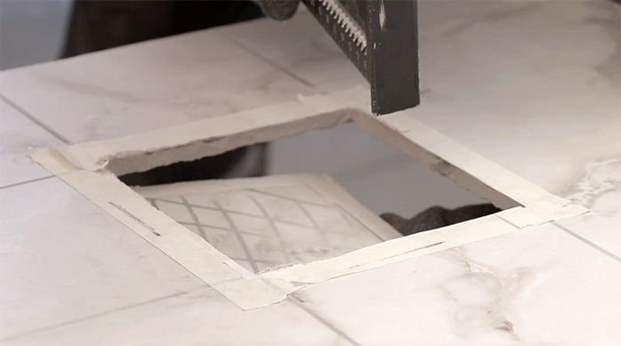 un hombre golpea el corte interior en la plancha de porcelanato para baños para que se suelte