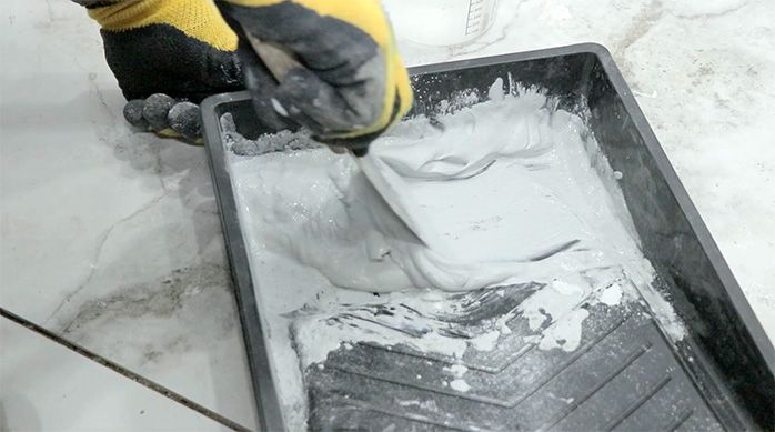 un hombre hace la mezcla de fragüe para aplicarla en el porcelanato