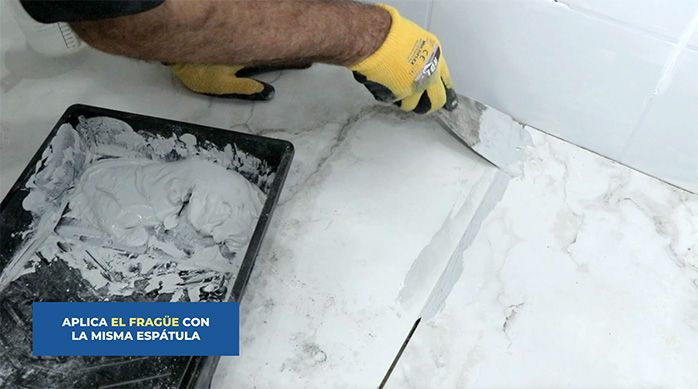 un hombre aplica fragüe en las junturas del porcelanato de piso