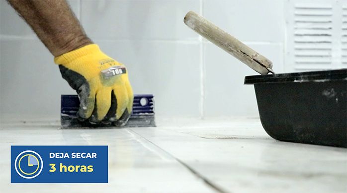 un hombre pasa un lengüeta de goma para retirar el exceso de fragüe del porcelanato de piso