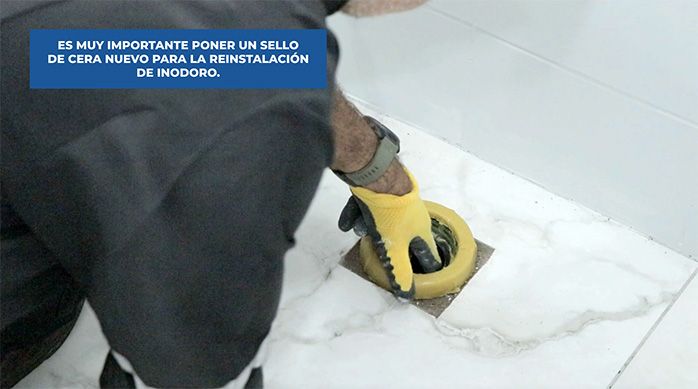 un hombre pone un sello de cera para inodoro en el desagüe del baño