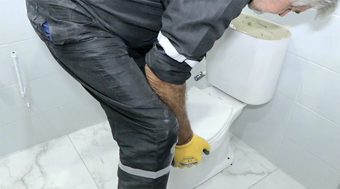 un hombre pone nuevamente el inodoro en el baño