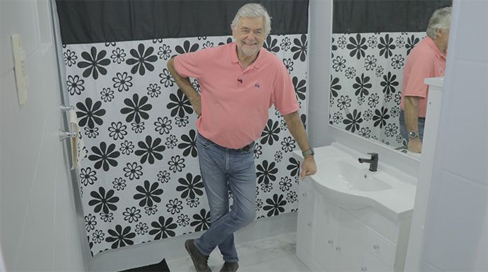un hombre en un baño con piso de porcelanato recién instalado