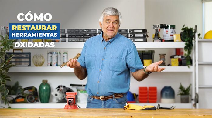 un hombre en un taller sujeta una llave inglesa oxidada