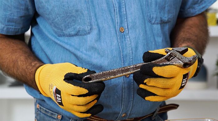 un hombre con guantes de seguridad sostiene una herramienta oxidada