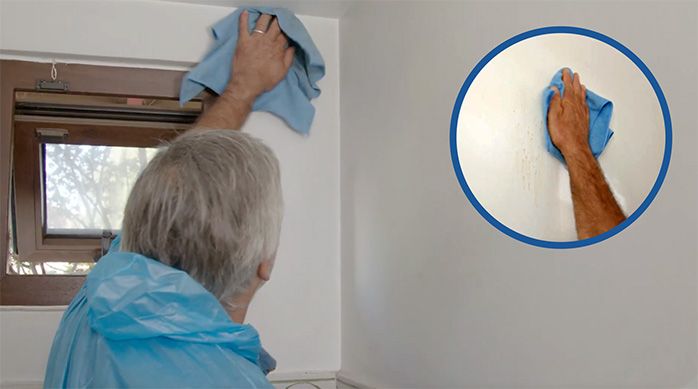un hombre limpia las paredes del baño de visitas con un paño de microfibra